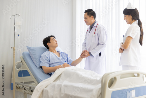 Professional male doctor and nurse caring visiting encourage male patient at hospital