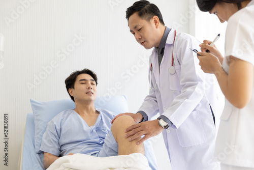 Professional orthopaedist male doctor and nurse visiting checking examine knee condition male patient at hospital