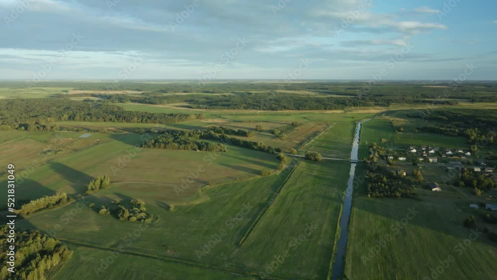 Flight over the river in the valley. A village in the middle of the forest is visible in the distance. In the light of the setting sun. Aerial photography.. Flight over the river in the valley. A village in the middle of the forest is visible in the distance. In the light of the setting sun. Aerial photography..
