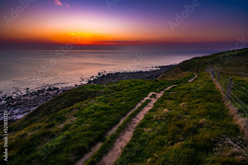 Colorful sunset with a narrow path in the foreground on the Atlantic coast at low tide in Normandy, France