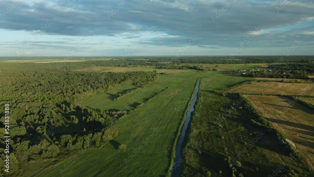 Flight over the river in the valley. A village in the middle of the forest is visible in the distance. In the light of the setting sun. Aerial photography. Flight over the river in the valley. A village in the middle of the forest is visible in the distance. In the light of the setting sun. Aerial photography.