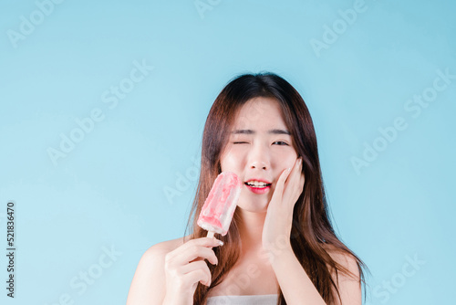 Wallpaper Mural Asian woman hold popsicle have a hypersensitive teeth on the blue background Torontodigital.ca