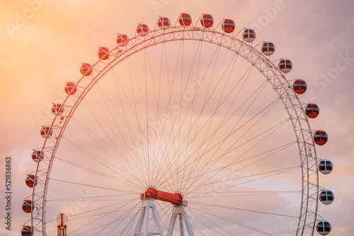 Ferris wheel in amusement park against sky background. Entertainment and fair concept. Close-up view of cabins and gondolas