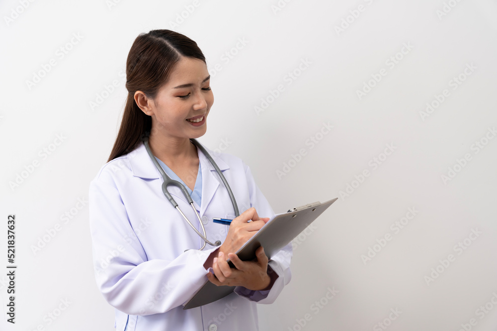 A long-haired brown-haired Asian female doctor in a white medical uniform smiling brightly, is standing with a paper board isolated against the background. A long-haired brown-haired Asian female doctor in a white medical uniform smiling brightly, is standing with a paper board isolated against the background.