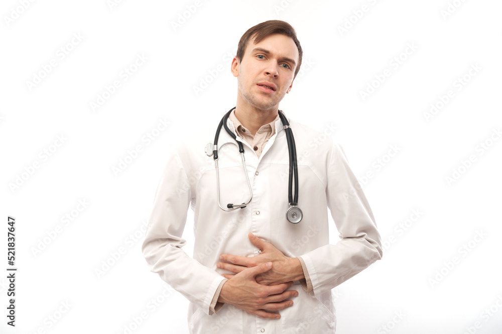 Portrait of sick doctor in white medical coat with stethoscope holding his stomach, isolated on white background with copy space