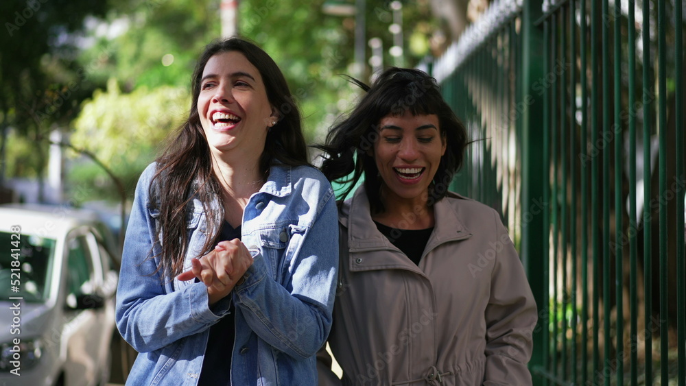 Naklejka premium Two happy female friends walking outside. Carefree girls walk in urban street together