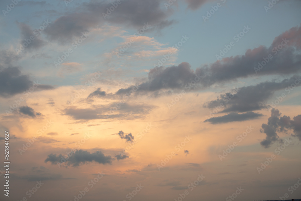 Blue sky with golden light and clouds at sunset.