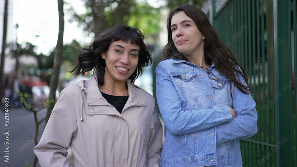 Two women in conversation walking in city street. Female friends talking Two women in conversation walking in city street. Female friends talking
