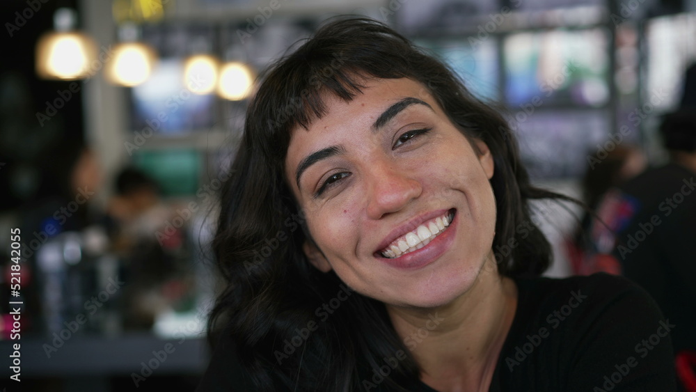 Portrait of a hispanic latin girl smiling at camera sitting at restaurant cafe