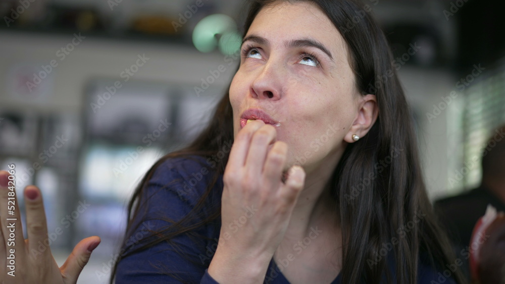 Person eating fries. Happy woman eats fast food meal at restaurant. Girl taking a bite of french fry Person eating fries. Happy woman eats fast food meal at restaurant. Girl taking a bite of french fry