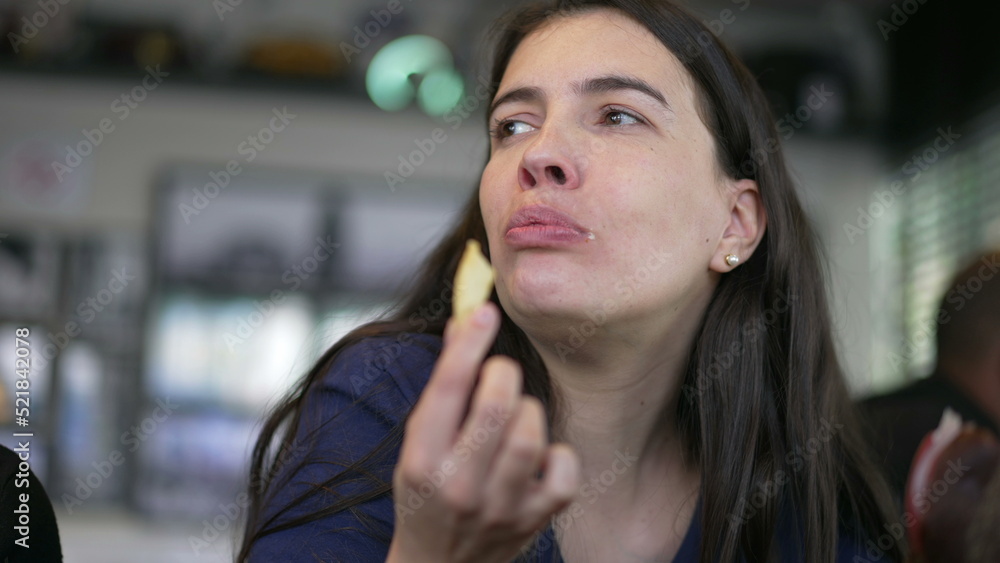 Person eating fries. Happy woman eats fast food meal at restaurant. Girl taking a bite of french fry
