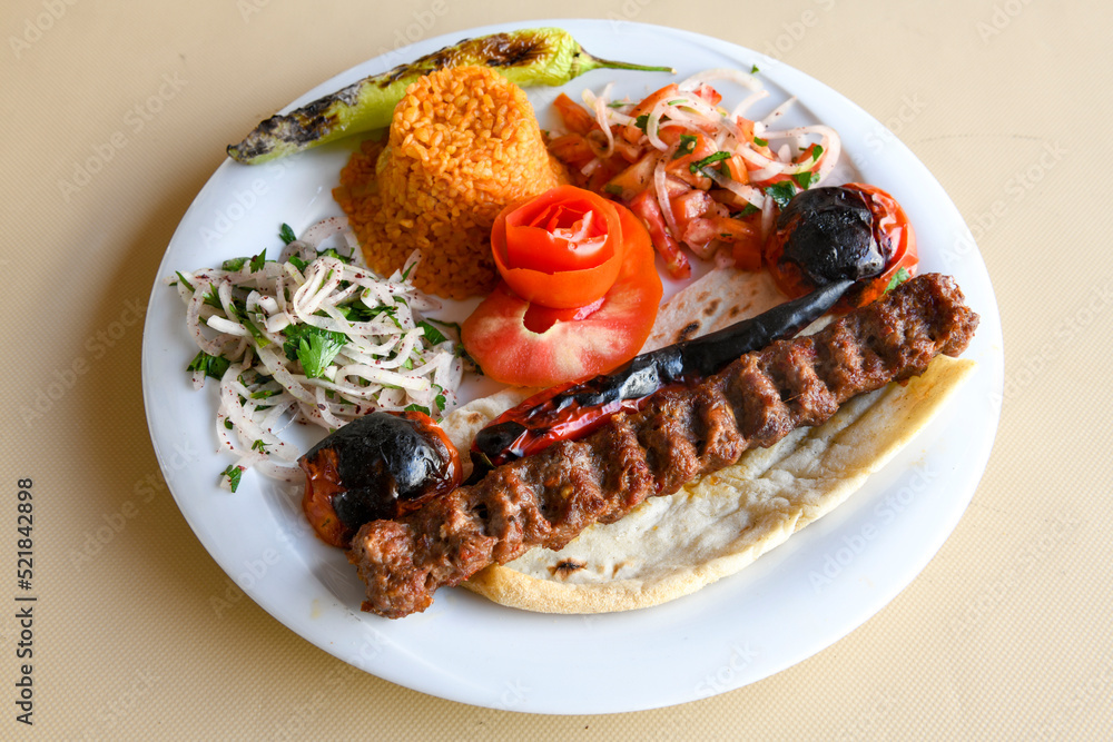 Grilled Turkish Adana, Urfa Kebab with grilled vegetables, onion and rice on plate. Adana durum . Grilled Turkish Adana, Urfa Kebab with grilled vegetables, onion and rice on plate. Adana durum .