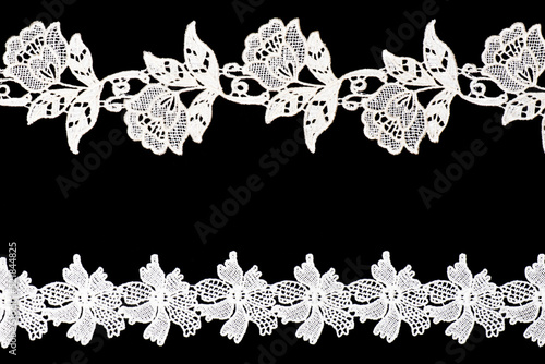 White lace with flowers and leaves isolated on black background horizontally