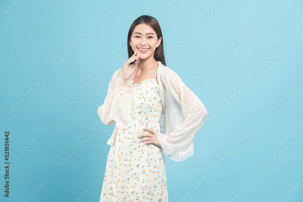 Beautiful young asian woman in white dress with flower pattern isolated on blue background Beautiful young asian woman in white dress with flower pattern isolated on blue background