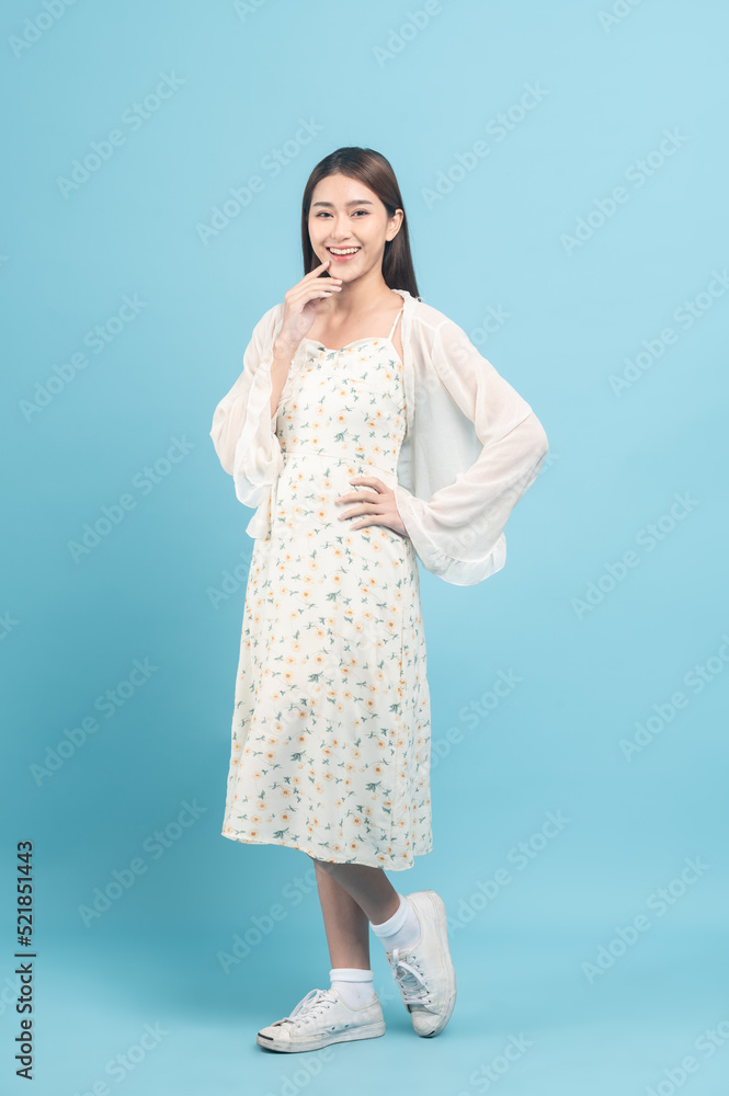 Beautiful young asian woman in white dress with flower pattern isolated on blue background Beautiful young asian woman in white dress with flower pattern isolated on blue background