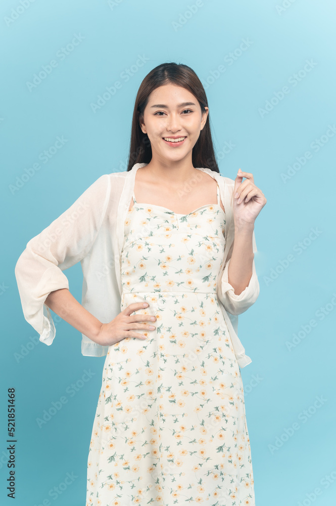 Beautiful young asian woman in white dress with flower pattern isolated on blue background Beautiful young asian woman in white dress with flower pattern isolated on blue background