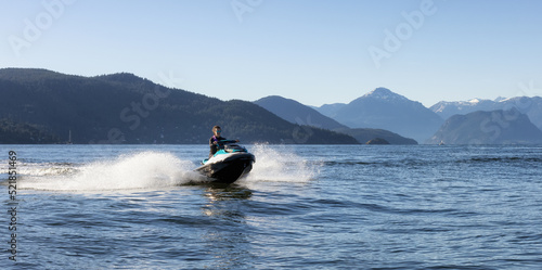 Adventurous Caucasian Woman on Water Scooter riding in the Ocean. Howe Sound and mountain landscape in background. West Vancouver, British Columbia, Canada.