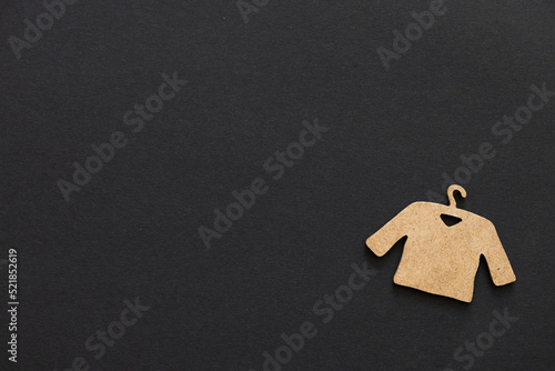 A wooden figure of a clothes hanger on a black background. Shopping concept