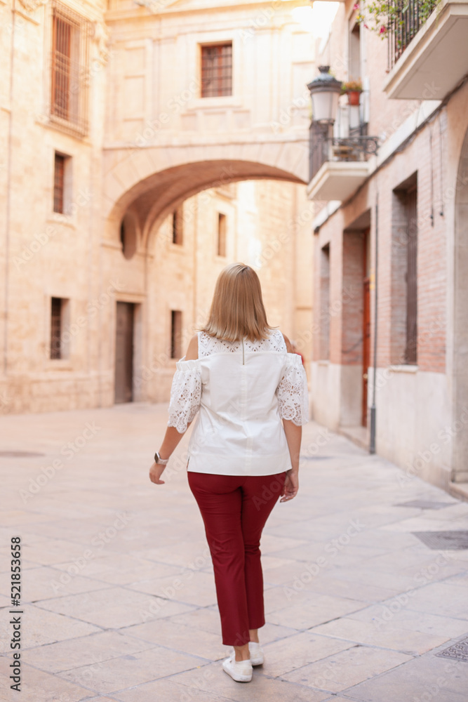 Rear view on woman walking in the historic center. Tourism in Europe
