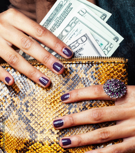 pretty fingers of african american woman holding money close up with purse, luxury jewellery on python clutch, cash for gifts