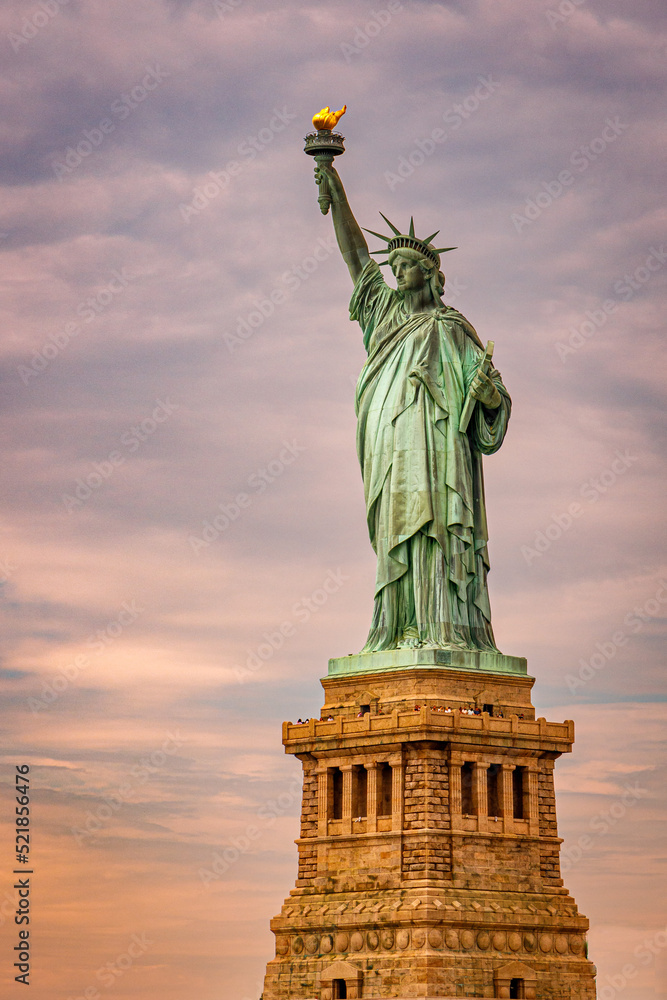 Fototapeta premium Red glow of clouds around the statue of liberty on a warm summer morning in New York City