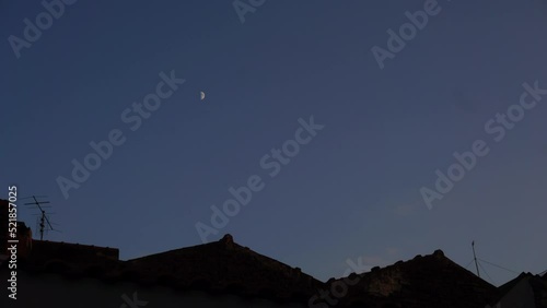 Time lapse delle nuvole e della luna che tramonta dietro i tetti con le tegole rosse, tipici siciliani photo