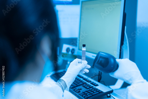 Woman scientist hand holding test tube barcode and scanner for automatic analysis machine in laboratory.Biologist working in modern laboratory with technological equipment.