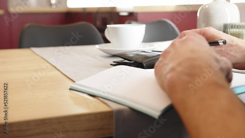 Writing with a pen.
The man is writing in the notebook.