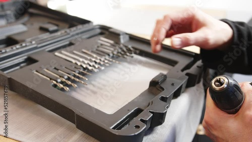 Replacing the drill bit in the screwdriver. The man is putting on the drill.