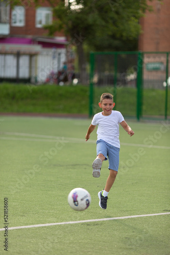 A boy kicks a soccer ball on the school football field