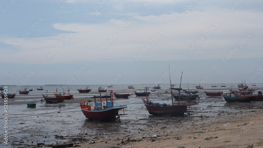 small fishing boat low tide, small boat out to sea with colored flags attached in the sea in Thailand. small fishing boat low tide, small boat out to sea with colored flags attached in the sea in Thailand.