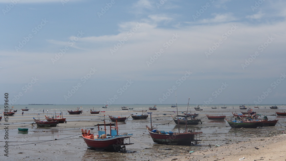 Fototapeta premium small fishing boat low tide, small boat out to sea with colored flags attached in the sea in Thailand. 