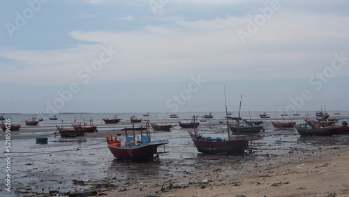 small fishing boat low tide  small boat out to sea with colored flags attached in the sea in Thailand. 