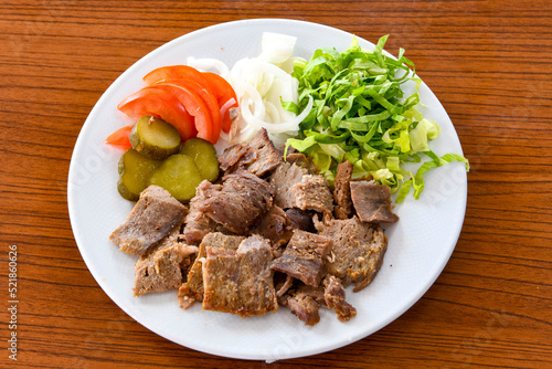 Turkish and Arabic Traditional Ramadan doner kebab with tasty tomato sauce and rice or turkish pilav in white plate on wood table background. ( Pilav ustu doner)