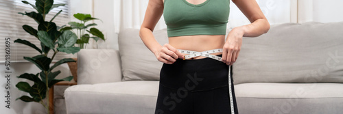 Φωτογραφία Sporty woman in sportswear is measuring waist circumference and looking on tape