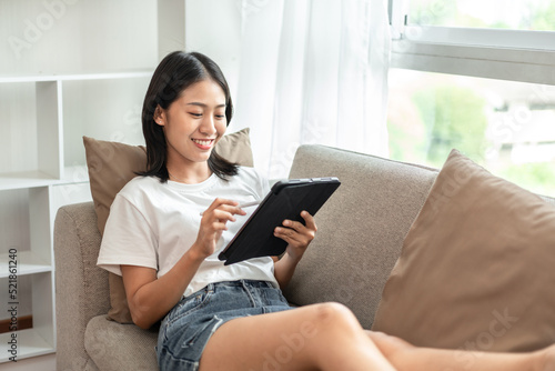 Half-Japanese woman sitting on the sofa using tablet while on vacation, Rest at home, Living room, Relax time, Touch screen tablet, Go on internet, Favorite corner, Personal space