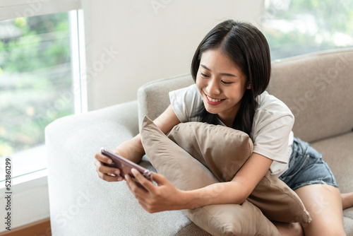 Half-Japanese woman sitting on the sofa using mobile while on vacation, Rest at home, Living room, Relax time, Touch screen tablet, Go on internet, Favorite corner, Personal space