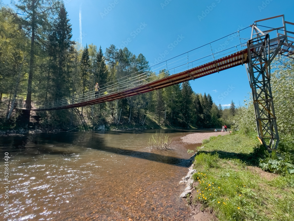 Man on a suspension bridge over a river in a natural park