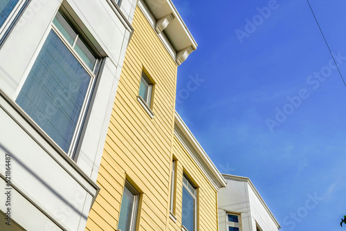 Low angle view of a townhouse with yellow wood lap sidings in San Francisco, California