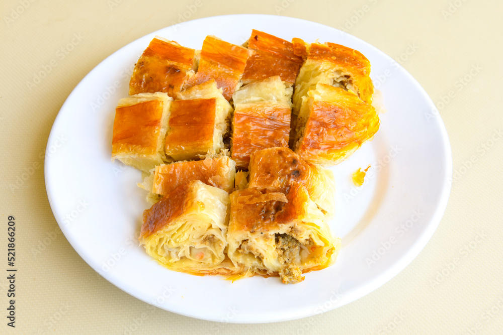 Turkish style meat stuffed filo dough borek served kol boregi. Cheese and minced pie are sliced on a marble background. Turkish name: Kol Boregi, kiymali, peynirli su boregi. Turkish style meat stuffed filo dough borek served kol boregi. Cheese and minced pie are sliced on a marble background. Turkish name: Kol Boregi, kiymali, peynirli su boregi.