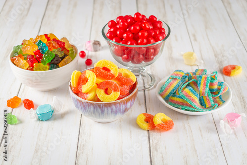 Assortment of candy in bowls on a light wood background
