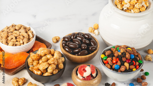 Snack spread on marble countertop with nuts, fruit, puffs, choco