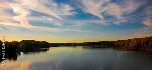 Sunset on the lake. Beautiful nature, lake, forest and clouds. Reflections in the water. Realistic illustration © Evgenii