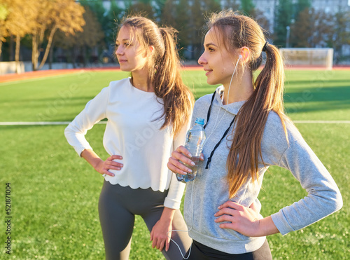 Two girls in sportswear posing at the stadium.Portrait of two sports girlfriends at the sports stadium.