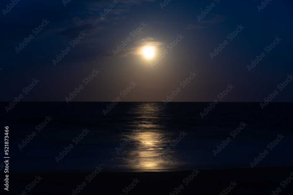 Beach at night with moon in sky