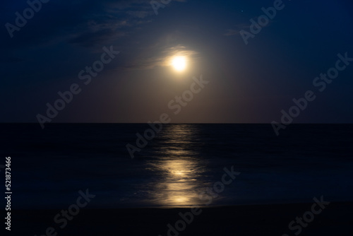 Beach at night with moon in sky © Alex P