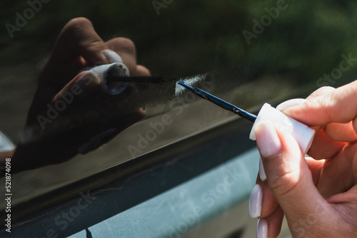 Touching up a body car with a small brush by a young woman