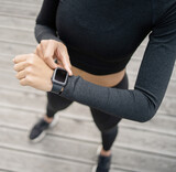 Uses a fitness watch on her arm, a female athlete runs does an active workout on the street