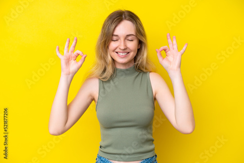 Blonde English young girl isolated on yellow background in zen pose