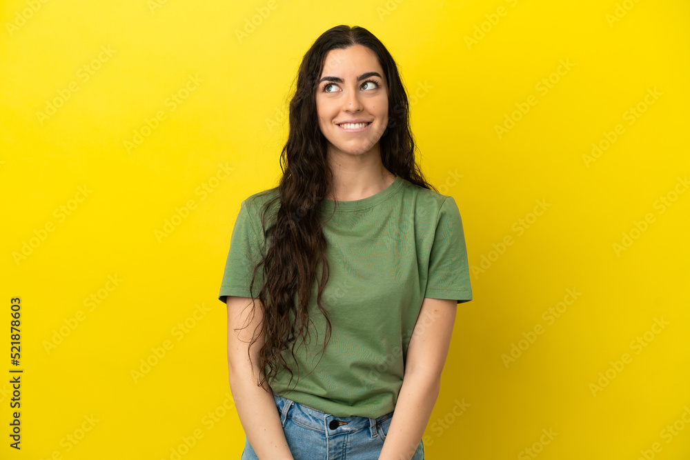 Young caucasian woman isolated on yellow background having doubts while looking up Young caucasian woman isolated on yellow background having doubts while looking up